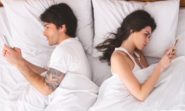unhappy European/White couple using their phones in bed unhappy European/White couple using their phones in bed