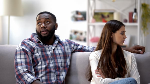 unhappy African/Black man and European/White lady looking away from each other in the living room